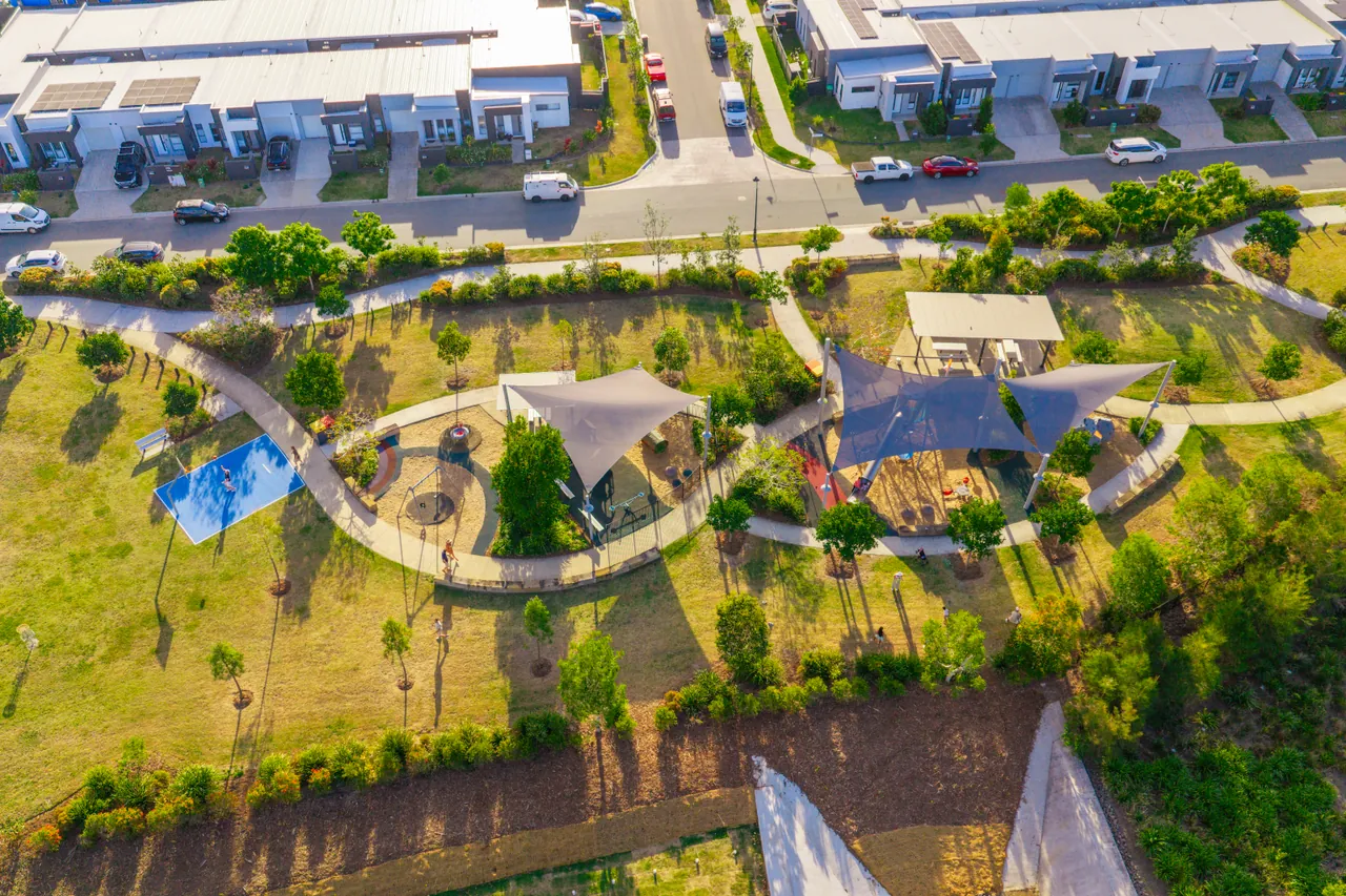 An aerial view of a park with shade sails, paths and surrounding homes