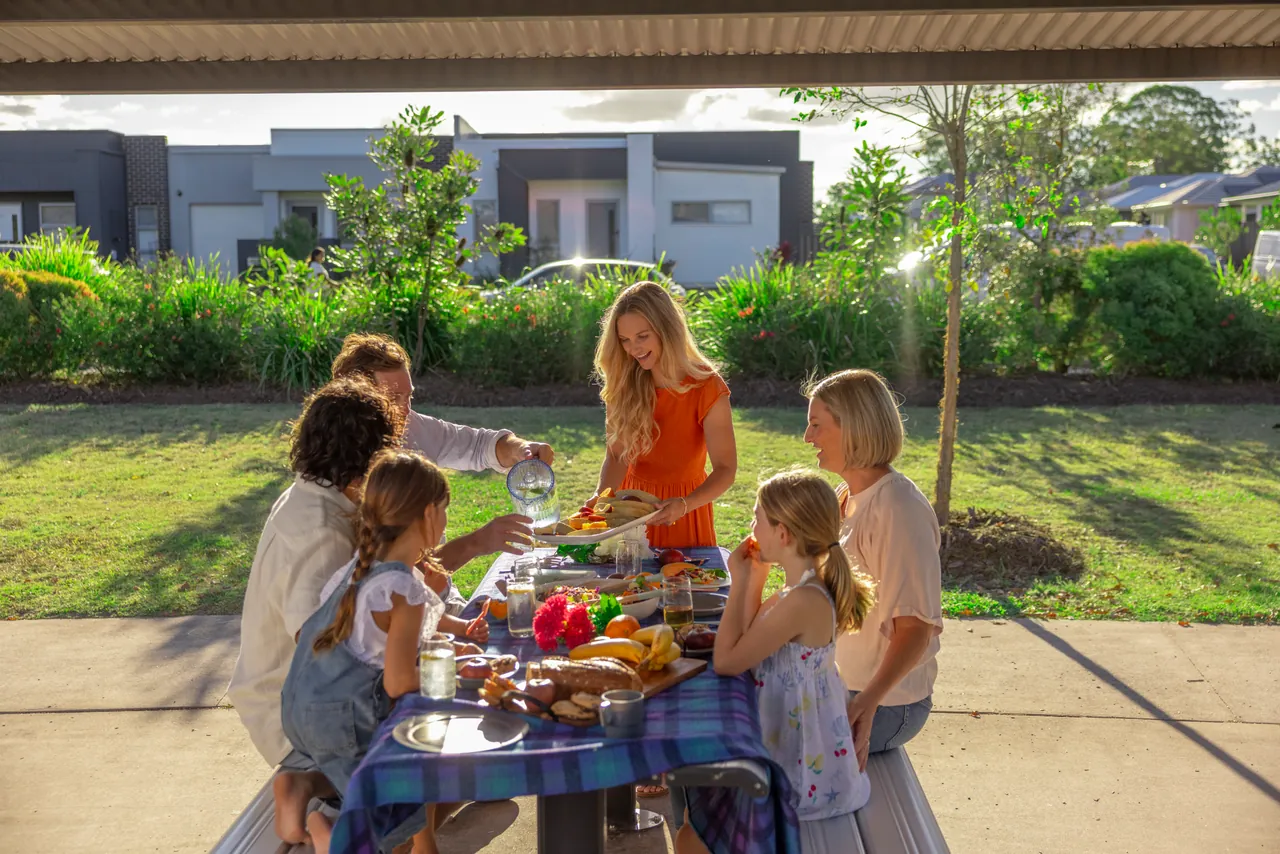 A family sharing lunch at a picnic table under a park shelter