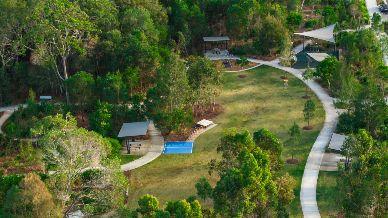 An aerial view of established parkland with paths, shelters and mature trees
