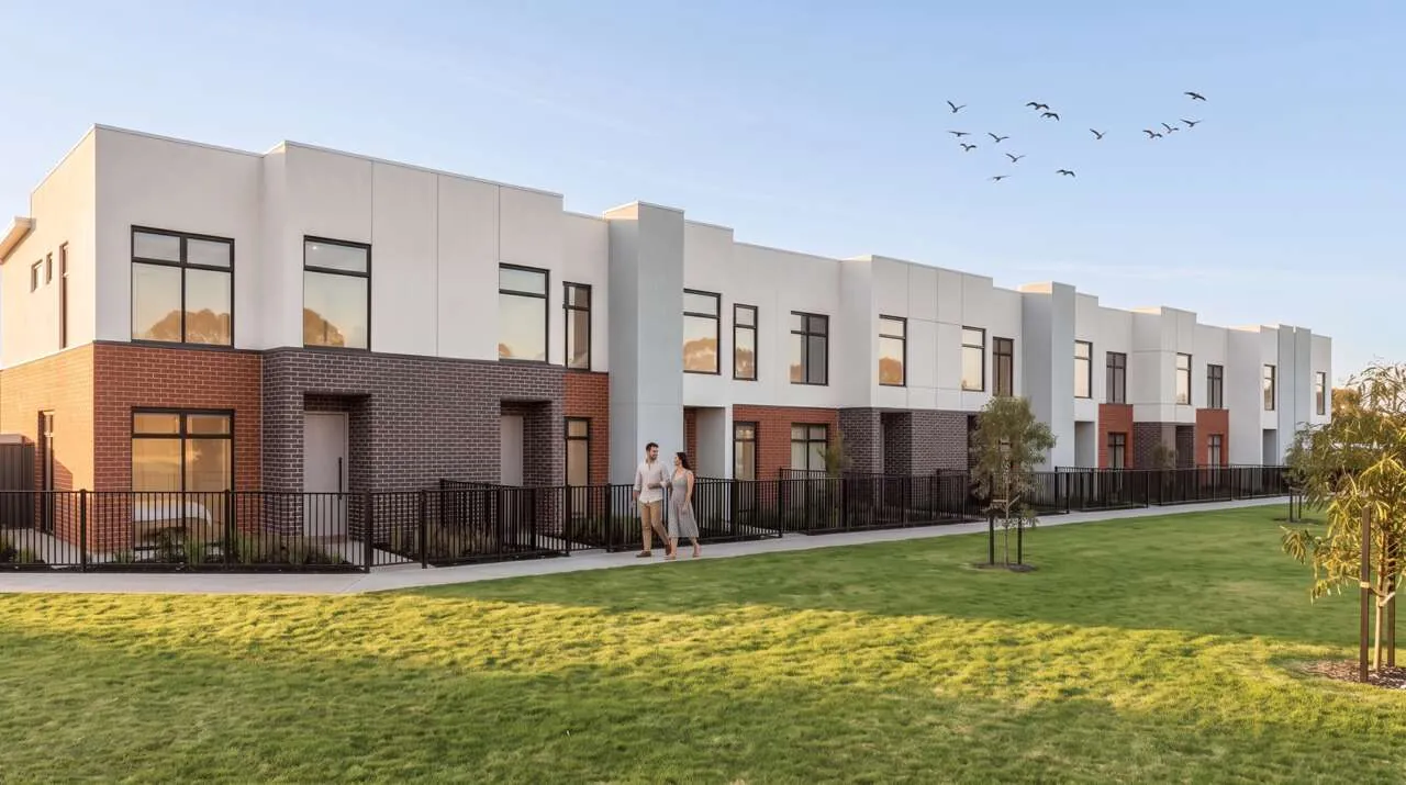A couple walking past a row of new two-storey terrace homes beside a lawn