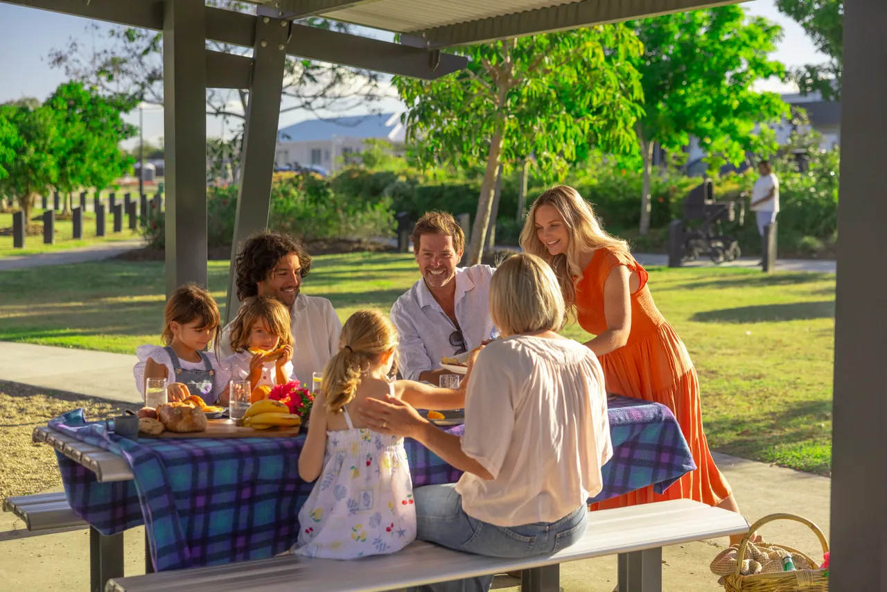 A family sharing a picnic at a table under a park shelter