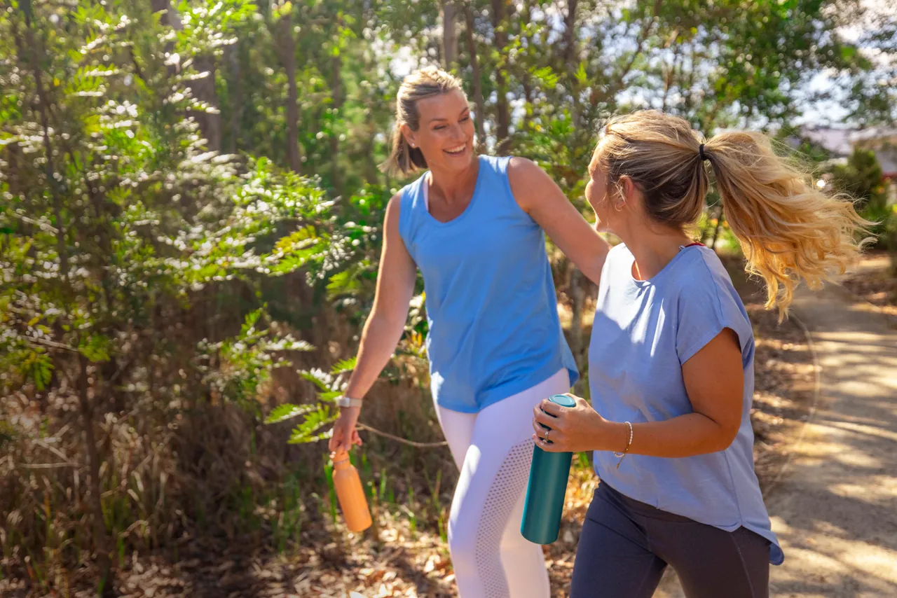 Two women laughing as they walk along a bush track